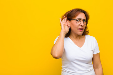 middle age woman looking serious and curious, listening, trying to hear a secret conversation or...
