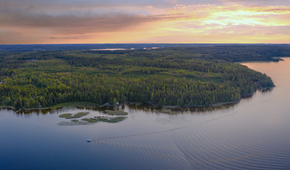Aerial view of Pulkkilanharju Ridge, Paijanne National Park, southern part of Lake Paijanne. Landscape with drone. Blue lakes, boat and green forests from above on a sunset in Finland.