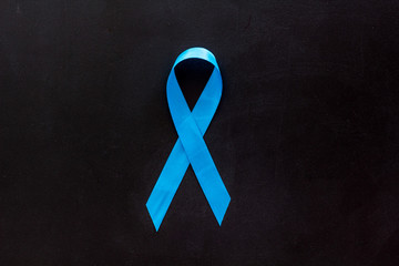 Blue ribbon as symbol disease control on black background top view copy space