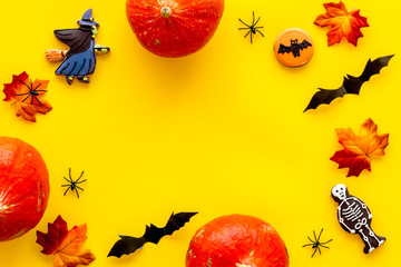 Halloween frame with pumpkins, paper bats and special cookies on yellow background top view space for text