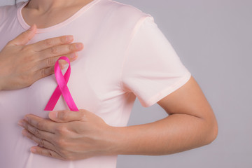 Closeup of pink badge ribbon on woman chest to support breast cancer cause. Healthcare, medical and...