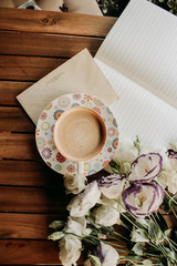 cup of coffee, notebook and white flowers on a wooden table