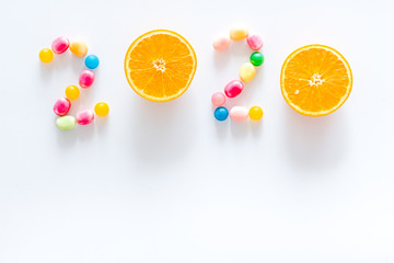 Sweet New Year design. 2020 laid out with candy and oranges on white background top view copy space