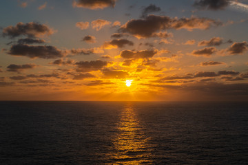 Naklejka na ściany i meble God rays in a orange sunset at sea