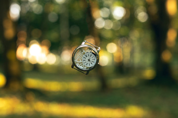 inspiring graphic design picture of vintage hand clock in the air on golden fairy tale forest unfocused bokeh natural background environment