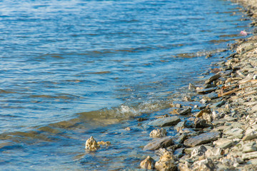 simple natural scenic background view of stone coast line near blue water lake surface 