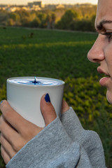 Water drop column rising out of her drinking mug elicits a scowl expression from the female teen holding the cup.