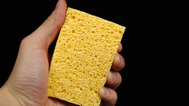 Showing a yellow sponge for dishwashing on a black background