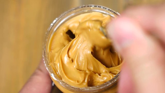 Creamy smooth peanut butter in jar backdrop. Mixing with a Spoon peanut butter