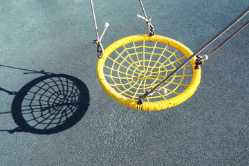 Yellow swing in the form of a web and a shadow from it. Minimalism...