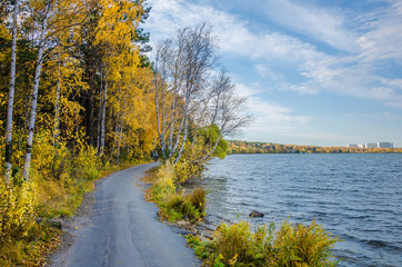 The road along the lake near the forest in autumn.