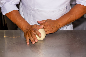 Two Man hands knead a bread dough, in close captation. In a professional chefs kitchen. 