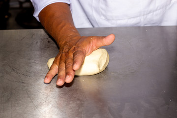 Man hands knead a bread dough, in close captation. In a professional chefs kitchen. 