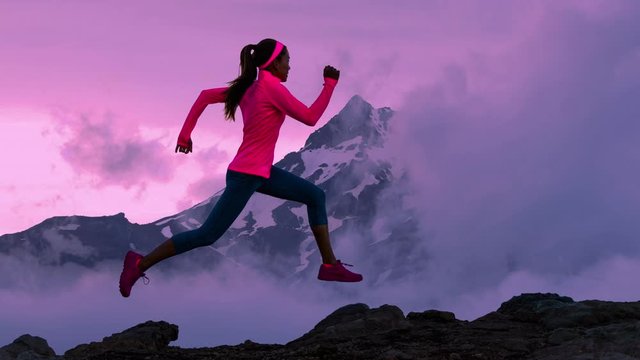 CINEMAGRAPH - seamless loop. Trail runner athlete silhouette running in mountain summit background clouds and peaks. Woman on run training outdoors active fit lifestyle. Looping Motion photo image.