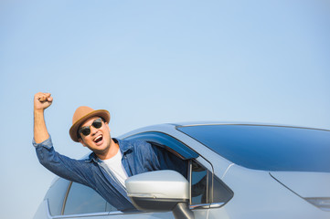 Young handsome asian man driving car to travel on his holiday vacation time with beautiful blue sky.