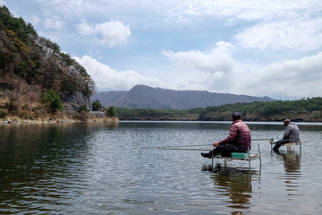 Senior fisherman goes fishing , the Men are  fishing by sitting on the chair above the Saiko lake  ,one of the fuji five lakes in Japan