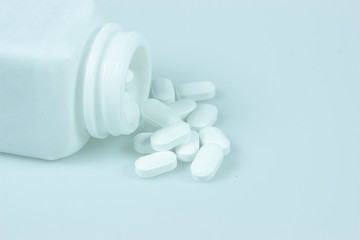 Opioid epidemic, painkillers and drug abuse concept with close up on a bottle of prescription drugs and hydrocodone pills falling out of it on white