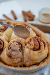 Cinnamon rolls with sugar frosting. With cinnamon sticks and spices, wooden background 