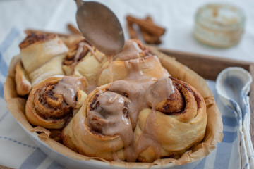 Cinnamon rolls with sugar frosting. With cinnamon sticks and spices, wooden background 