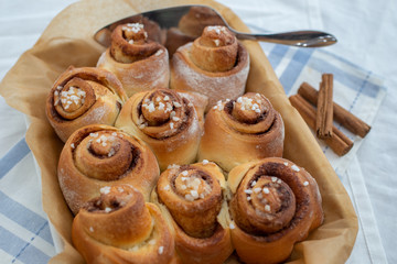 Cinnamon rolls with sugar frosting. With cinnamon sticks and spices, wooden background 
