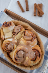Cinnamon rolls with sugar frosting. With cinnamon sticks and spices, wooden background 