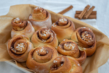 Cinnamon rolls with sugar frosting. With cinnamon sticks and spices, wooden background 