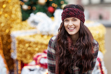 Beautiful joyful woman portrait in a city. Smiling  girl wearing warm clothes and hat  in winter or autumn. Christmas time with  unfocus lights on backgrounde. Copy space