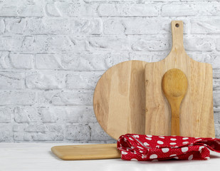Set of kitchen wooden cutting boards and red kitchen napkin in polka dot pattern. Wooden boards on kitchen table against wall. Concept of cooking. Copy space.
