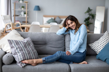 Happy casual beautiful woman sitting on a sofa at home.