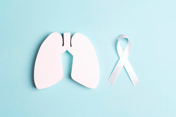White lung cancer awareness ribbon and lung symbol on blue background.