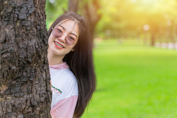 Fototapeta premium Happy Asian dental braces girl wearing sunglasses happy hide and seek at tree park outdoor portrait.