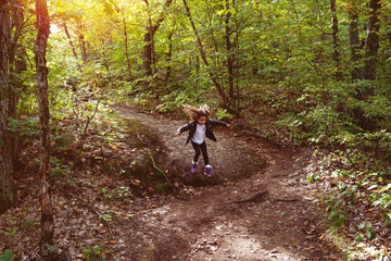 young girl jumping from rock in forest in autumn in park, slow shutter, motion blur. Gatineau Park, Quebec, Ontario.