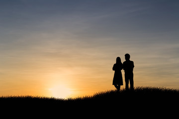 Fototapeta na wymiar Silhouettes of couple man and woman in nature sunset background. Love concept.
