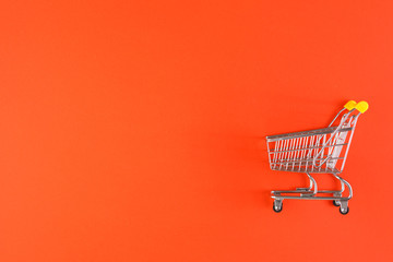 Shopaholic. Buyer. Shopping concept. Close-up. Isolated shopping trolley on a red background. Copy space.