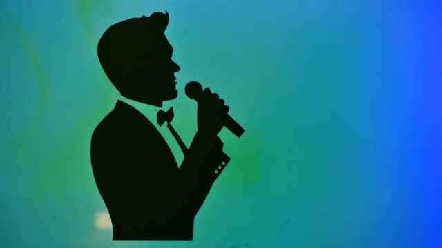 Silhouette of a male classical singer singing with a microphone in the studio,