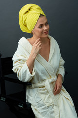 Smiling woman in bathrobe sitting on chair.