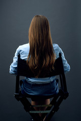 woman with long hair  sitting back on movies director chair.