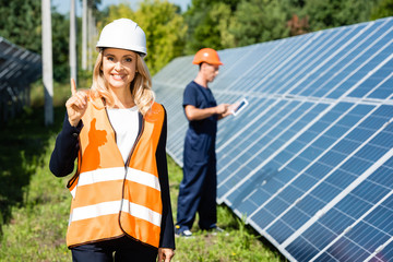 attractive businesswoman in hardhat smiling and showing idea gesture