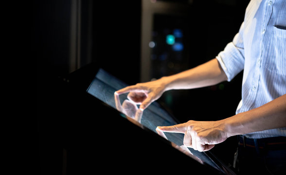 Close up of a hand touching to screen large display while consults about touristic information with copy space on black background. Interactive kiosk with public transport large building map.