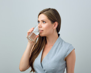 Young woman in business dress drinking water from glass.