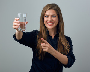 woman holding water glass in front of her and pointing with finger.
