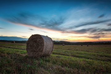 Autumn field at sunset / Magnificent sunset view with a field full of hay bales 