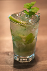 Refreshing mint cocktail mojito with rum and lime, cold drink or beverage with ice on white wooden background, top view