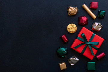 Cristmas background with gift box and colorful wrapped chocolate candy. Top view