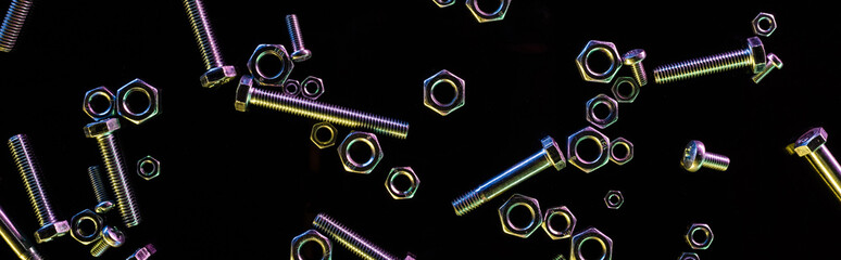panoramic shot of scattered metal nuts and bolts isolated on black