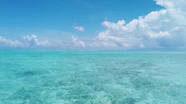 Seamless Loop video: Beautiful ocean seascape against sky. Turquoise sea waves in crystal clear water in reef lagoon. Stunning blue ocean during sunny day.