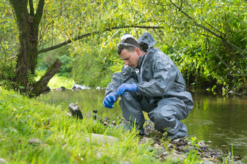 mobile laboratory specialist in a protective suit does a water analysis on the river bank