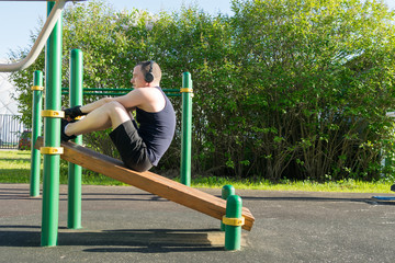a man plays sports on the site, does exercises to strengthen the press using an inclined bench