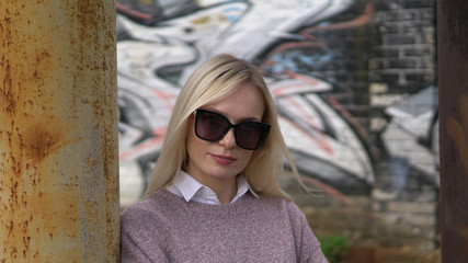 Showy woman in sweater posing among metal pillars .