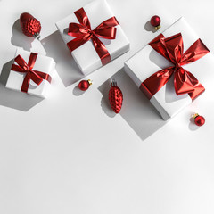 Christmas gift boxes with red ribbon and decoration on white background. Xmas and Happy New Year holiday, bokeh, light. Flat lay, top view, harsh shadow